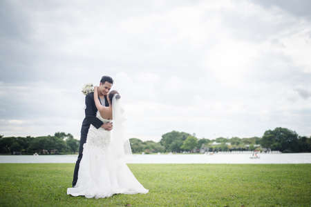 Happy smiling couple in wedding. Pretty Bride and handsome groom gorgeous posting in the nature.の写真素材