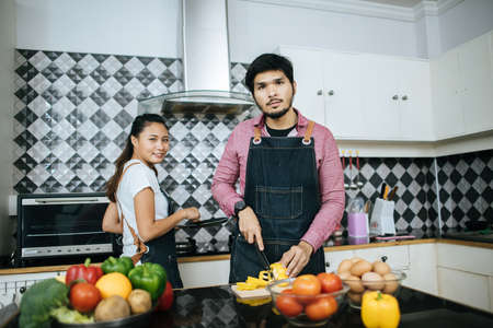 Happy smiling young couple cooking together in kitchen. Couple concept.の写真素材