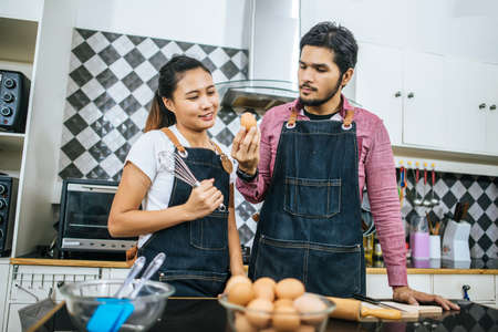 Happy young couple helping each other cooking in kitchen at home.の写真素材