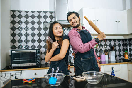 Attractive couple is cooking on kitchen at home. Preparing ingredients for cooking together at home.の写真素材