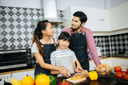Family cooking time : Happy mum teach her daughter chopping vegetable preparing ingredients for cooking meal in kitchen at home.の写真素材