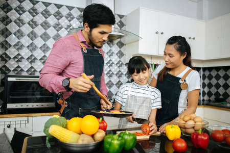 Family cooking time : Happy family help cooking meal together in kitchen at home.の写真素材