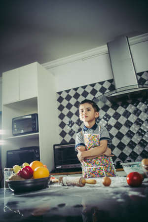 Cute Little boy learn how to cook standing in the kitchen at home.の写真素材