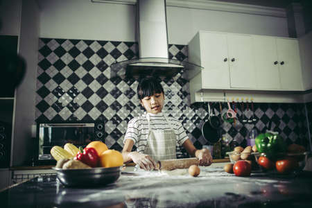 Little chef using rolling pin stretching the dough. Cooking concept.の写真素材
