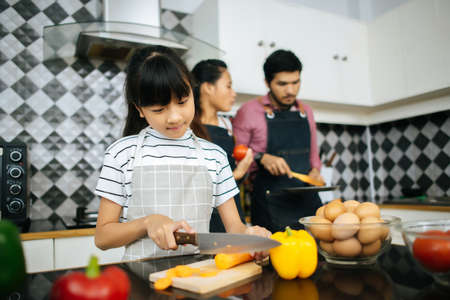 Family cooking time : Happy mum teach her daughter chopping vegetable preparing ingredients for cooking meal in kitchen at home.の写真素材
