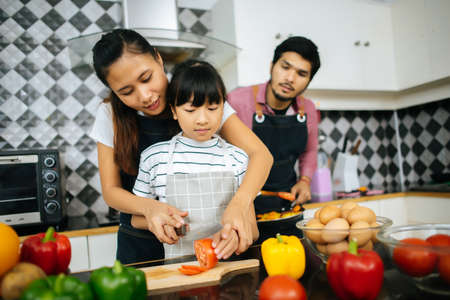 Family cooking time : Happy family help cooking meal together in kitchen at home.の写真素材