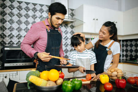 Family cooking time : Happy family help cooking meal together in kitchen at home.の写真素材