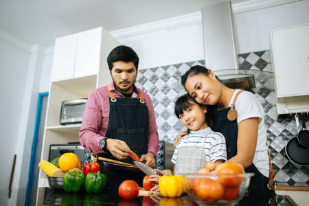 Family cooking time : Happy family help cooking meal together in kitchen at home.の写真素材
