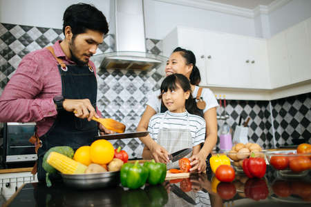 Family cooking time : Happy family help cooking meal together in kitchen at home.の写真素材