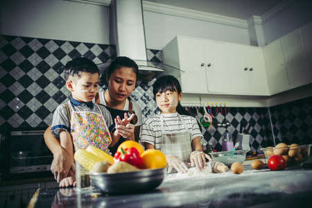 Family concept. Mum teach her children preparing the dough, bake homemade pizza.の写真素材