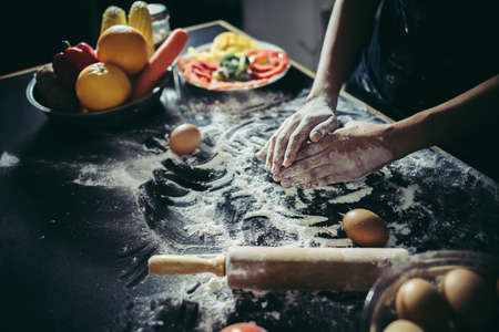Woman kneads dough for make pizza on wooden. Cooking concept.の写真素材
