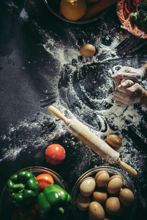 Woman kneads dough for make pizza on wooden. Cooking concept.の写真素材