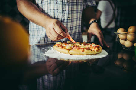 Close up of woman hand put topping on homemade pizza.の写真素材