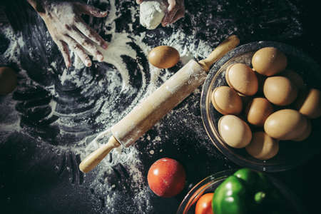 Woman kneads dough for make pizza on wooden. Cooking concept.の写真素材