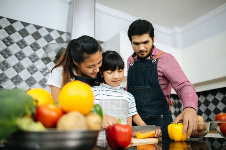 Family cooking time : Happy mum teach her daughter chopping vegetable preparing ingredients for cooking meal in kitchen at home.の写真素材