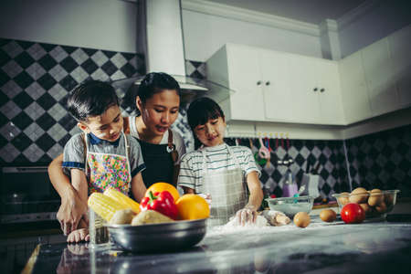 Family concept. Mum teach her children preparing the dough, bake homemade pizza.の写真素材