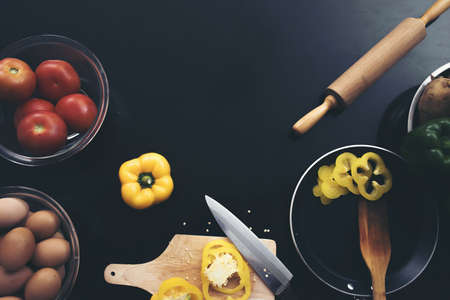 Fresh vegetables, eggs, and chopping bell pepper on black wood background. Mockup for menu or recipeの写真素材