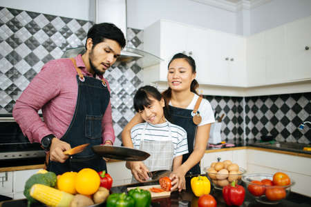 Family cooking time : Happy family help cooking meal together in kitchen at home.の写真素材