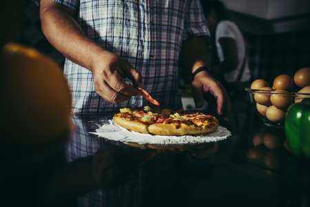 Close up of woman hand put topping on homemade pizza.の写真素材