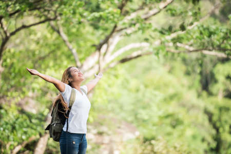 Young happy woman with backpack raising hand enjoy with nature. Woman travel concept.の写真素材