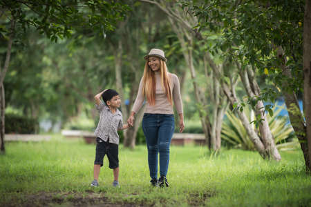 Portrait of mother and son happy walking together in the park holding hand. Family concept.の写真素材