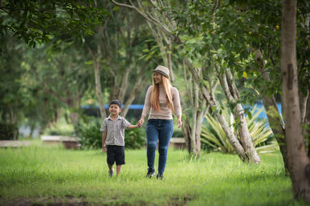 Portrait of mother and son happy walking together in the park holding hand. Family concept.の写真素材