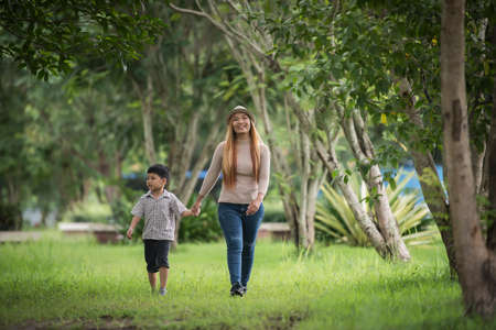 Portrait of mother and son happy walking together in the park holding hand. Family concept.の写真素材