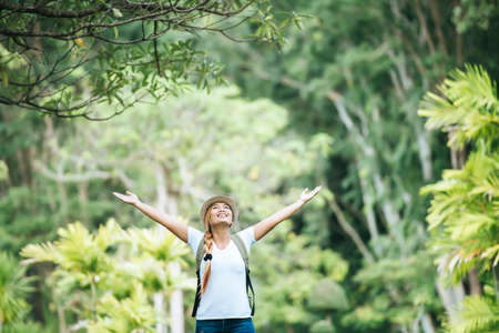 Young happy woman with backpack raising hand enjoy with nature. Woman travel concept.の写真素材