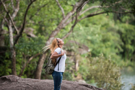 Young tourist woman with backpack enjoy nature standing on top of the mountain.の写真素材