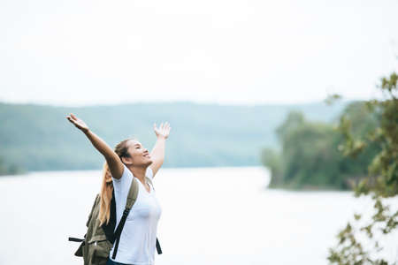 Tourist girl with arms happy with nature near the river. Travel concept.の写真素材