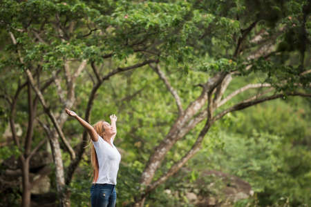 Young happy woman with backpack raising hand enjoy with nature. Woman travel concept.の写真素材