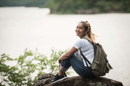 Young woman with backpack sitting enjoy with forest. Travel concept.の写真素材