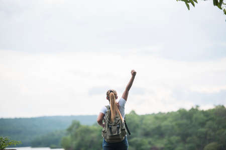 Close up back of tourist girl with arms raising happy with nature near lake. Travel concept.の写真素材