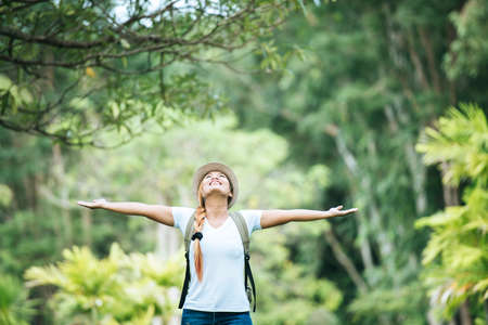 Young happy woman with backpack raising hand enjoy with nature. Woman travel concept.の写真素材