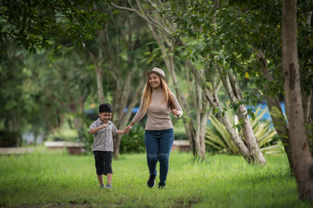 Portrait of mother and son happy walking together in the park holding hand. Family concept.の写真素材