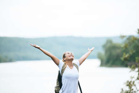 Tourist girl with arms happy with nature near the river. Travel concept.の写真素材