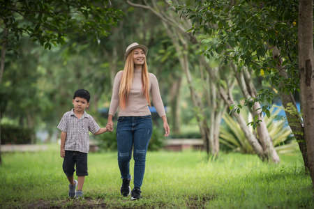 Portrait of mother and son happy walking together in the park holding hand. Family concept.の写真素材