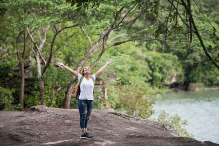 Young happy woman with backpack raising hand enjoy with nature. Woman travel concept.の写真素材