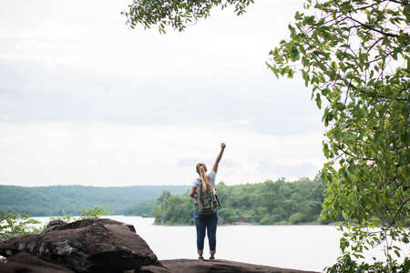 Close up back of tourist girl with arms raising happy with nature near lake. Travel concept.の写真素材