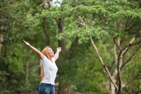 Young happy woman with backpack raising hand enjoy with nature. Woman travel concept.の写真素材