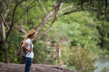 Young tourist woman with backpack feel lonely while standing on top of the mountain.の写真素材
