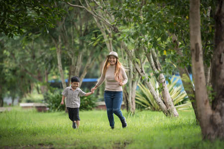 Portrait of mother and son happy walking together in the park holding hand. Family concept.の写真素材