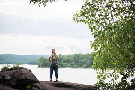 Close up back of tourist girl with backpack happy with nature near lake. Travel concept.の写真素材
