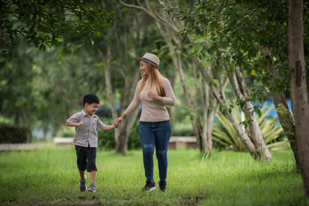 Portrait of mother and son happy walking together in the park holding hand. Family concept.の写真素材