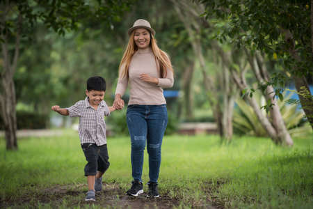 Portrait of mother and son happy walking together in the park holding hand. Family concept.の写真素材