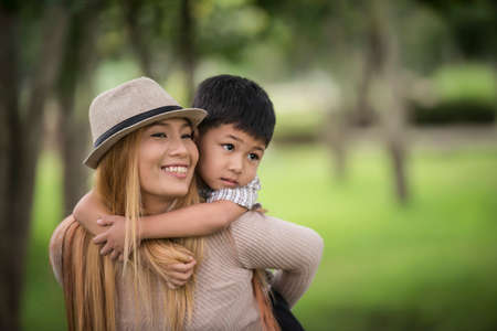 Happy young mother and son laughing little boy getting a piggyback ride on her back. Family concept.の写真素材