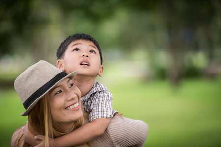 Happy young mother and son laughing little boy getting a piggyback ride on her back. Family concept.の写真素材
