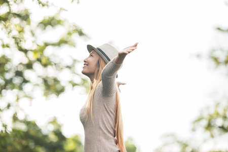 Young woman outdoor Raising hands enjoying nature. Woman lifestyle concept.の写真素材