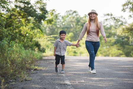 Close up of happy mum and son holding hand in a park. Family concept.の写真素材