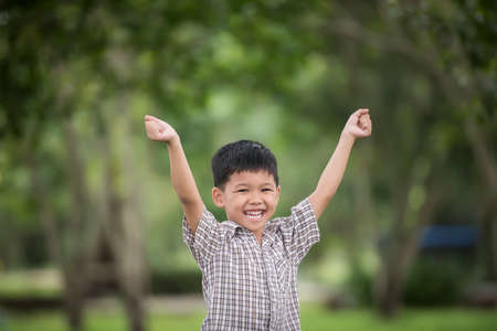 Little cute boy enjoying raising hands with nature over the blurred nature background.の写真素材